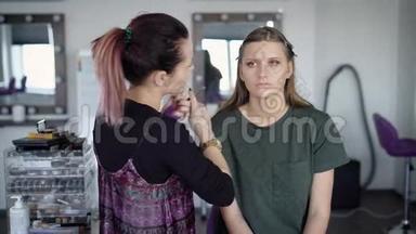 美妆工作室化妆申请工作流程。专业专家正在给女孩的脸上搽粉。年轻金发女郎